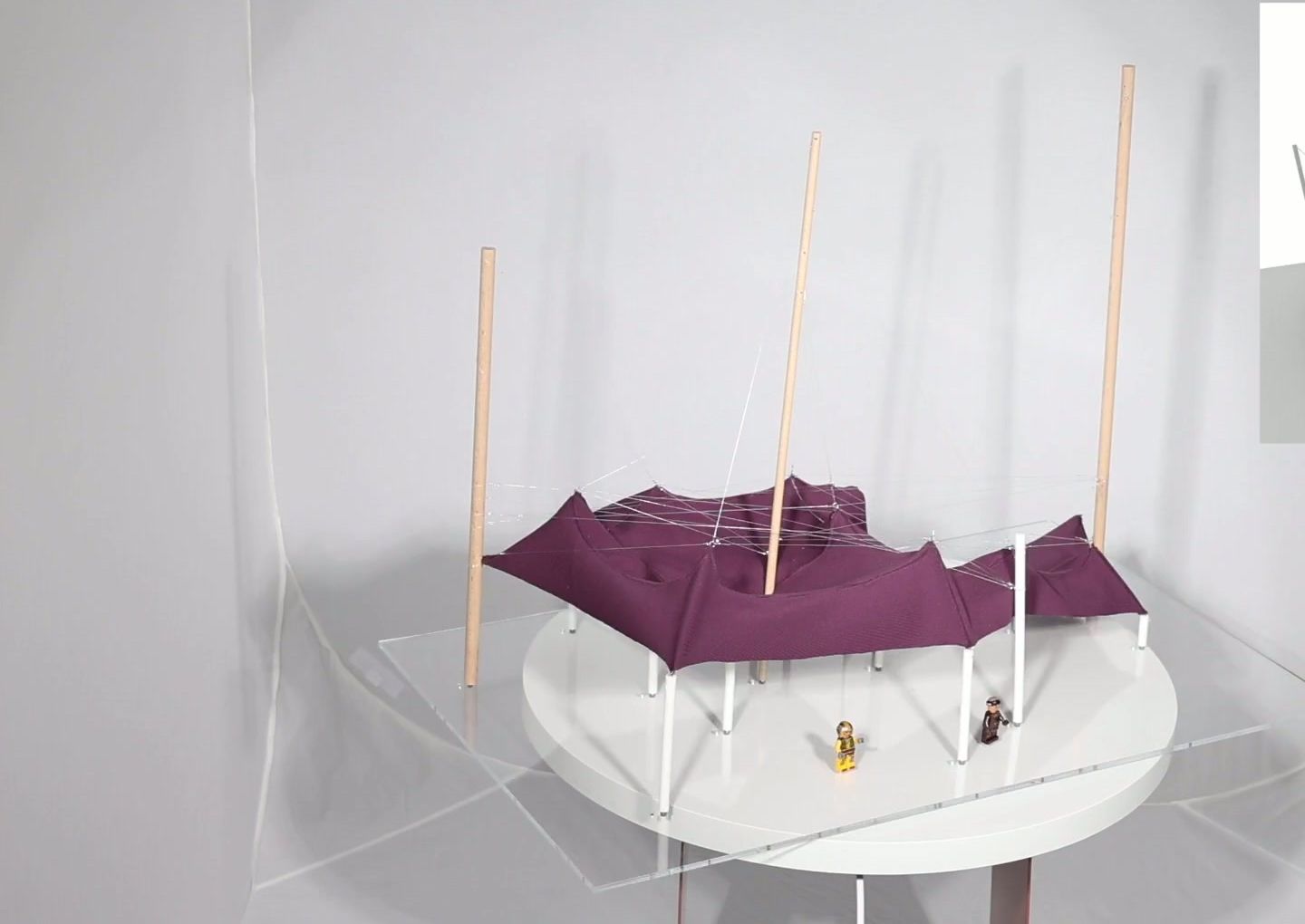 Physical prototype: a plum-coloured fabric tensile roof held by timber masts and cables