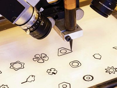 Robotic tool tracing cut-out shapes on a fabrication bed