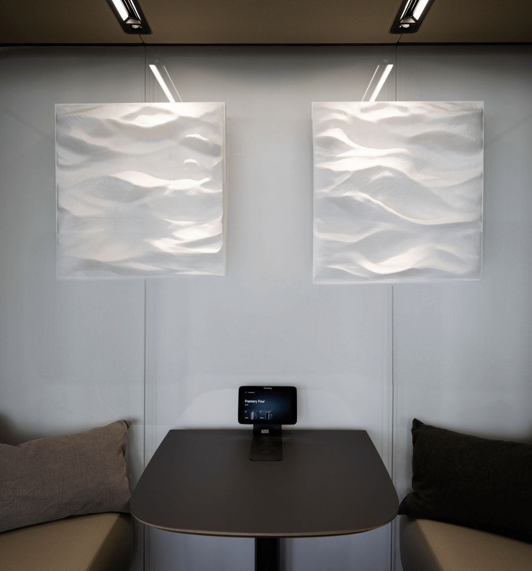 Two white acoustic relief panels with a wave pattern, installed on the wall of a meeting booth